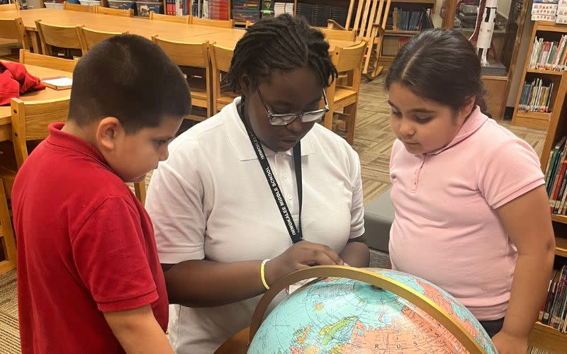 A Guadalupe Center Tutor Corps Program member, center, guides two younger students in a world geography lesson.