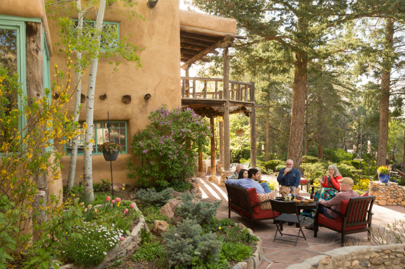 Group enjoying wine and cheese on the patio of the Inn with spring flowers and towering pine trees