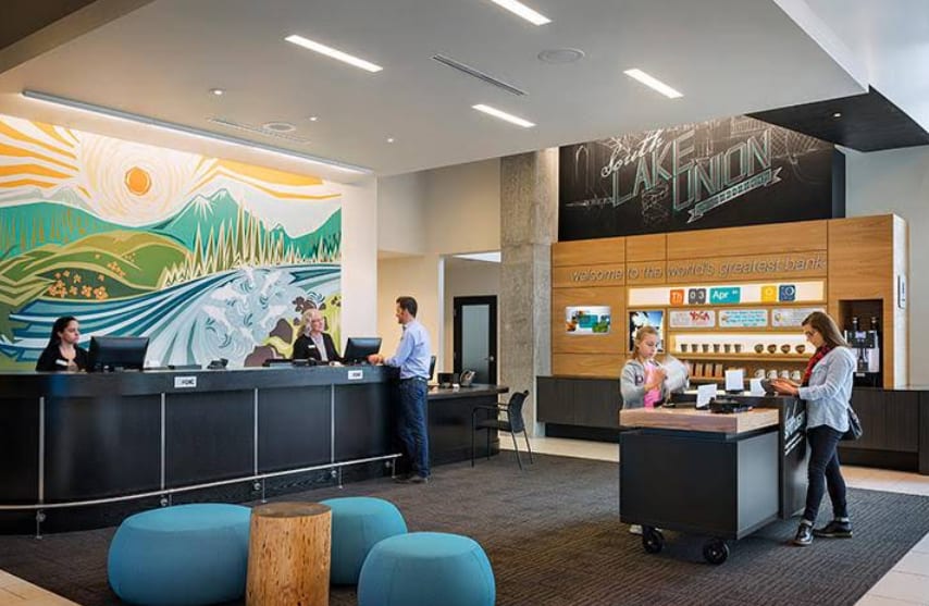 Interior of Umpqua Bank South Lake Union with scenic mural, teller counters, community board, and coffee station.
