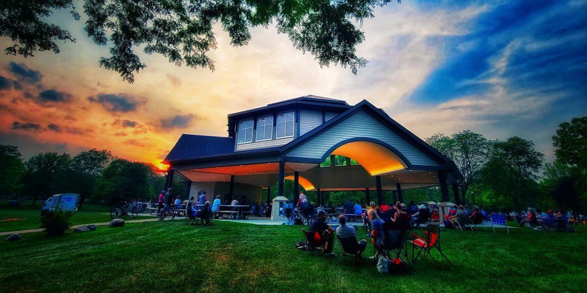 Band shell at sunset with people sitting on the lawn