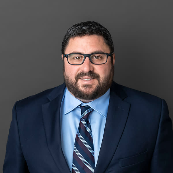 Joe Falcon headshot wearing a dark blue suit and glasses