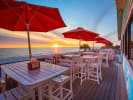 tables with umbrellas looking at the gulf during sunset