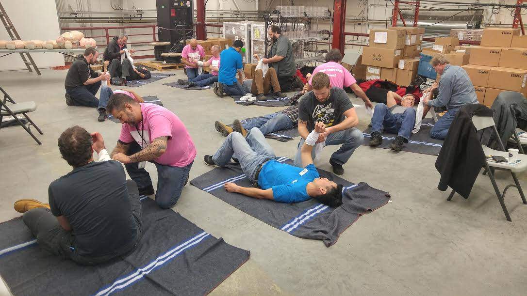 A first aid class showing several students applying bandages to their partners.