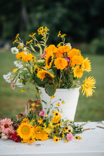 A mix of orange yellow and pink flowers in a bucket.