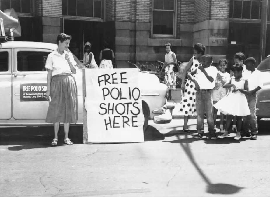 Sign stating Free Polio Shots Here. Children looking at the sign.