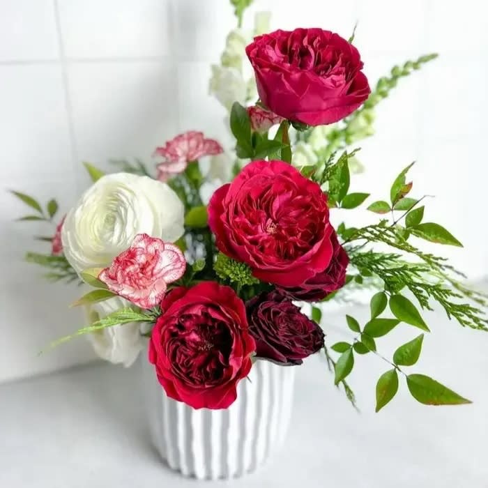 White vase on counter with bouquet of red and white flowers