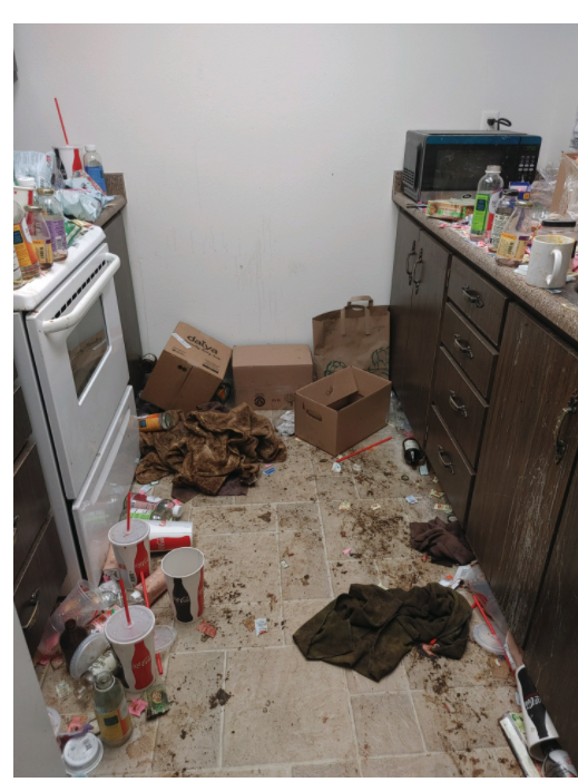 dirty kitchen area with trash and mess on the counters and floor