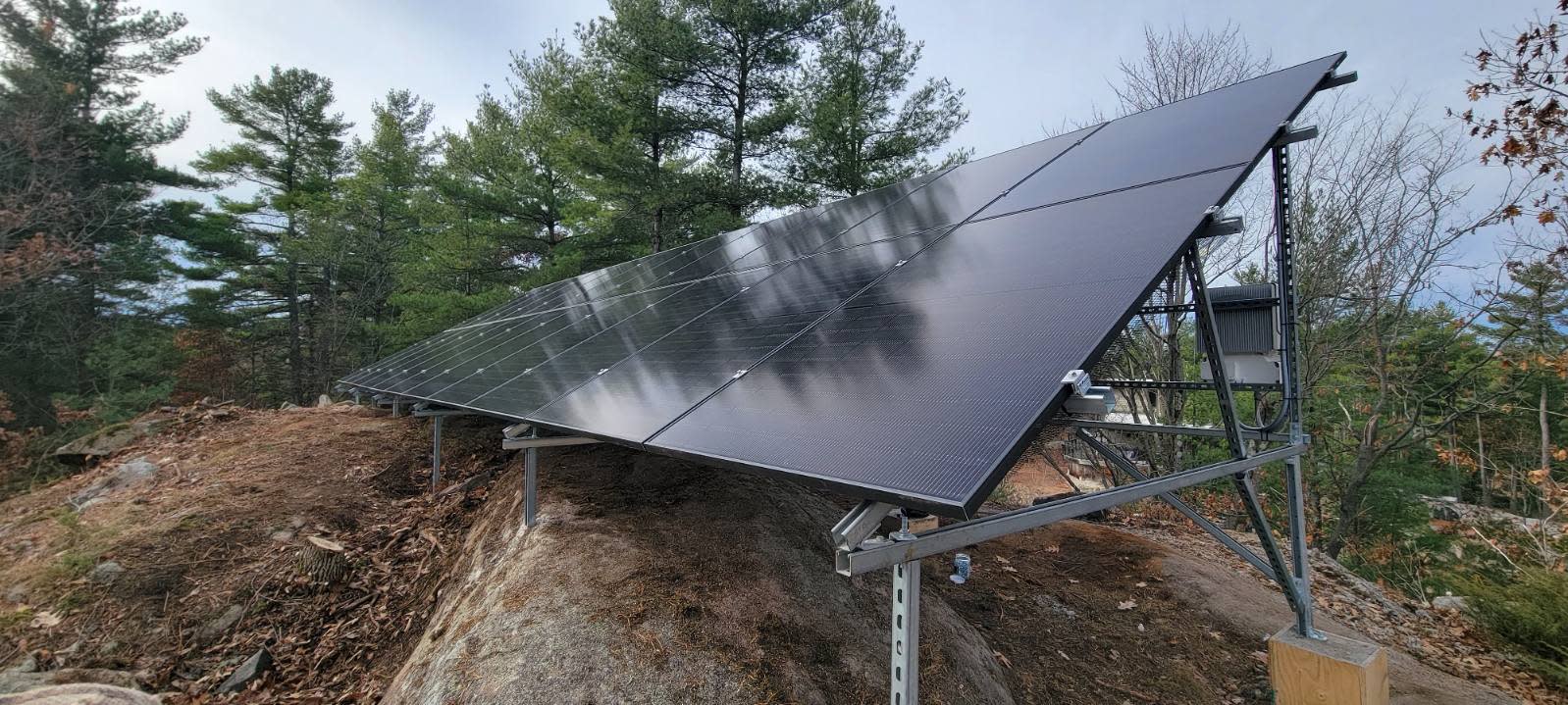 Black panels mounted into rock with tree reflection in panels
