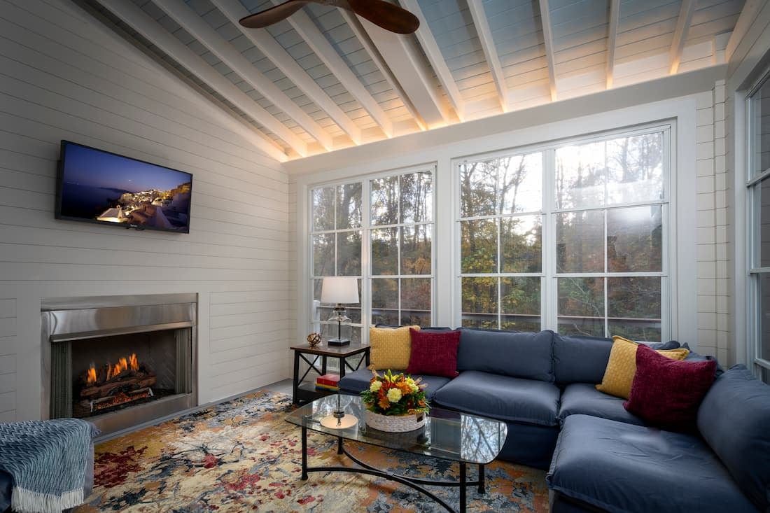 Screened porch with Eze Breeze windows and ventless fireplace by Distinctive Design + Build + Remodel for year-round comfort.