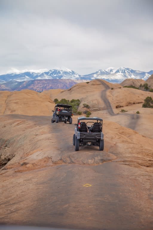 UTV driving through rugged desert terrain with red rock formations
