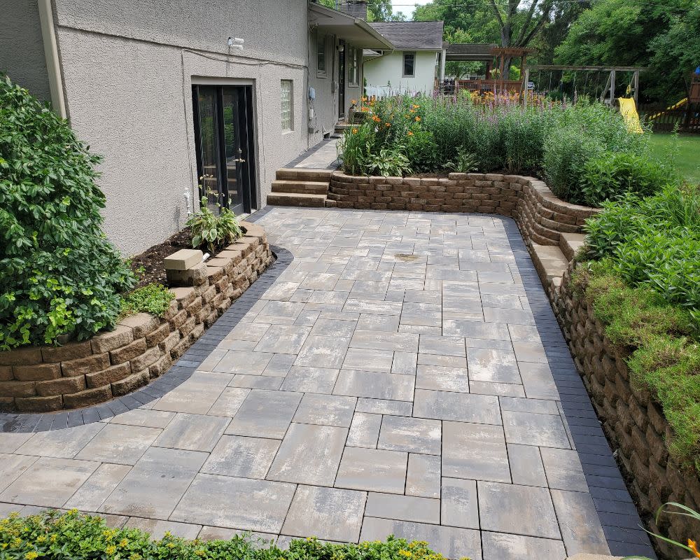 Paver Patio In Backyard With Surrounding Retaining Wall