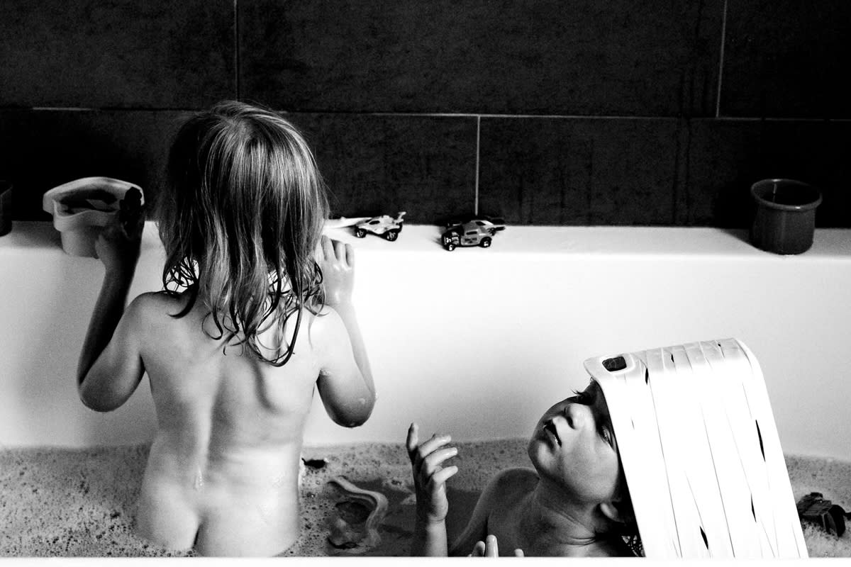 documentary photograph of twin boy and girl playing in bathtub