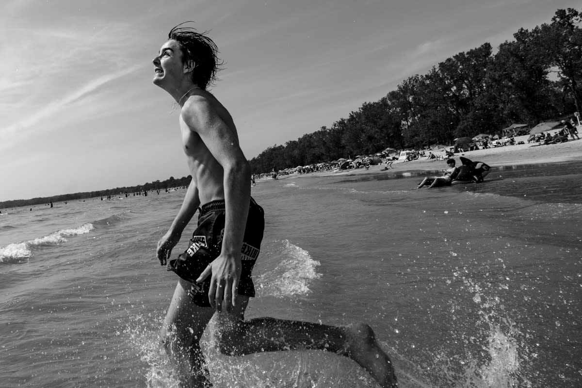 documentary photograph at Sandbanks Provincial Park teen boy splashing in the waves