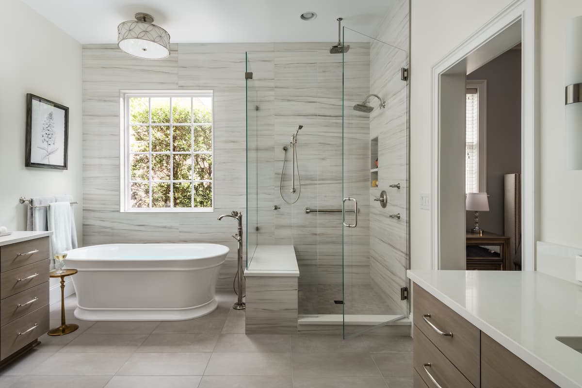 Master bathroom with tile feature wall, free-standing tub and a soothing colors by Distinctive Design + Build + Remodel.