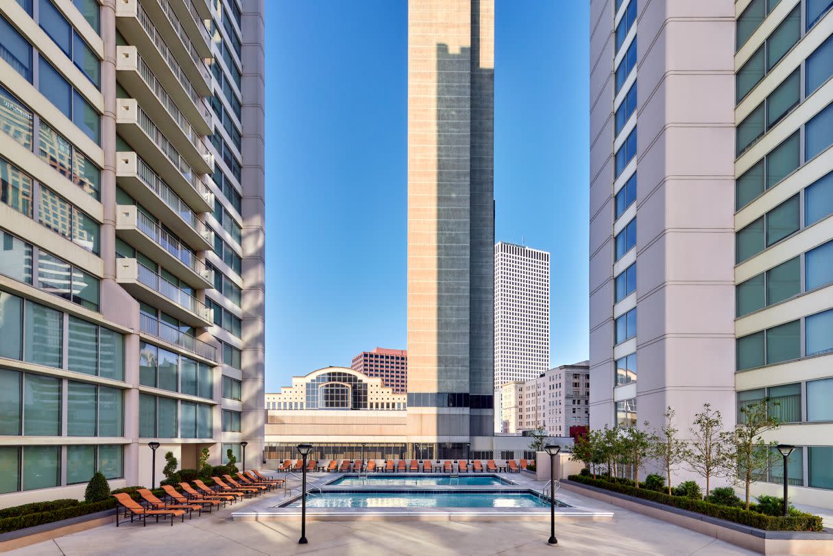 Photo of 5th floor outside between New Orleans Marriott towers shows rooftop pool, orange lounge chairs, & buildings