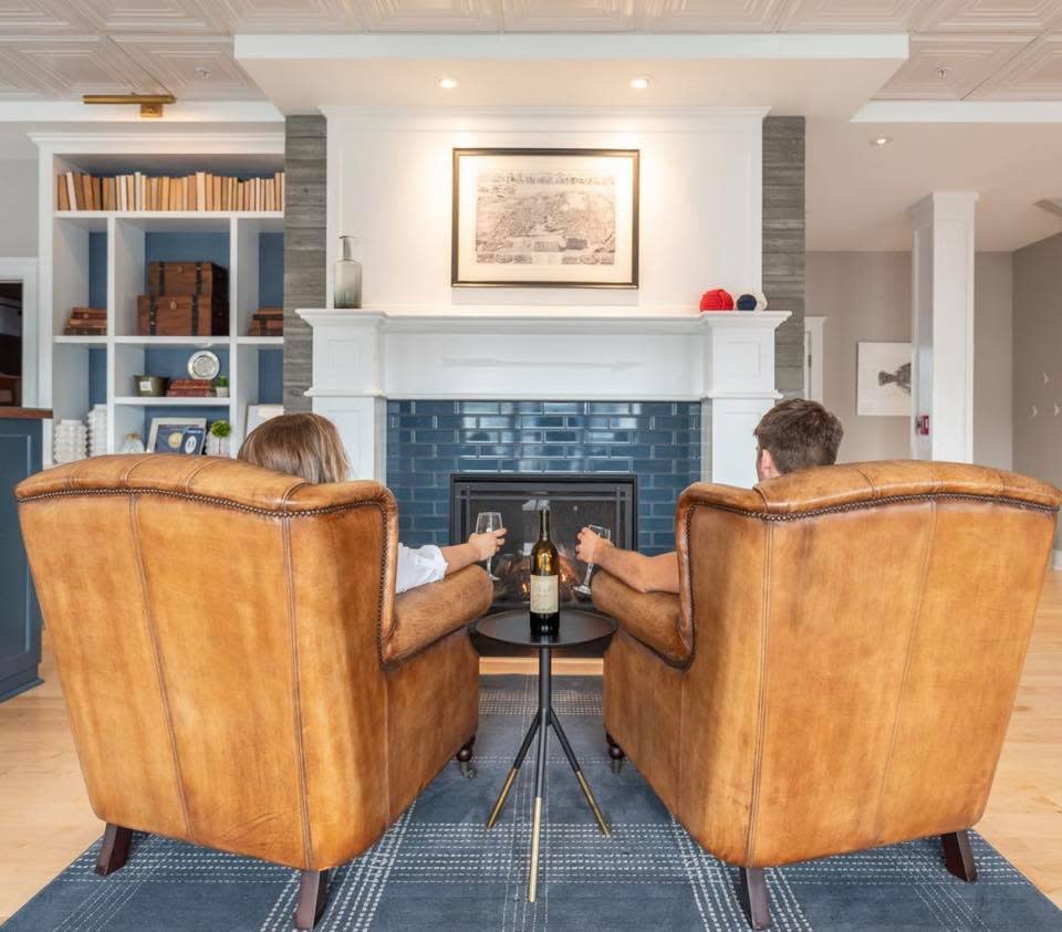two people sitting in front a fireplace in a hotel lobby in Mystic with glasses of wine