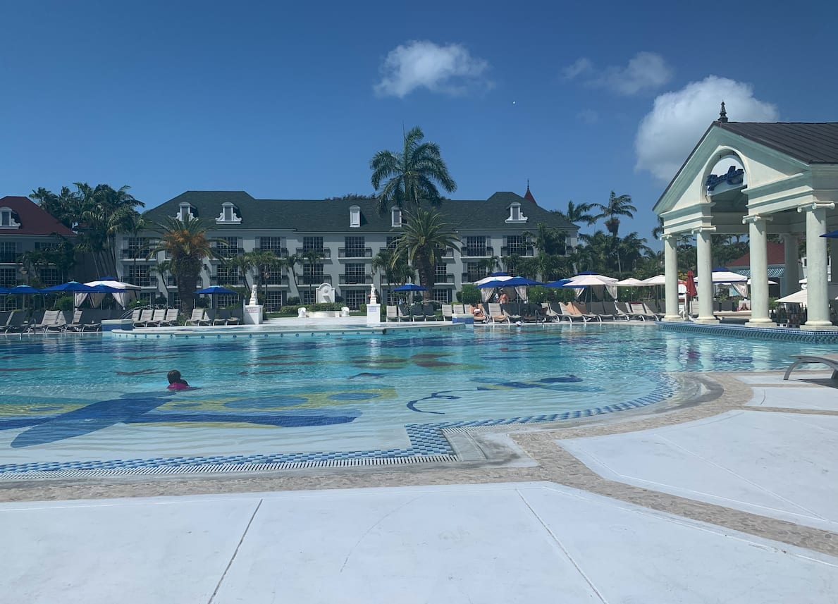 Large zero-entry resort pool, with loungers, umbrellas, and covered poolside bar