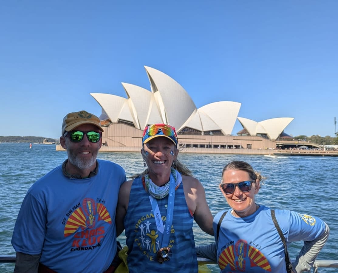 a man and two women standing on a ferry with the Sydney Opera House in the background
