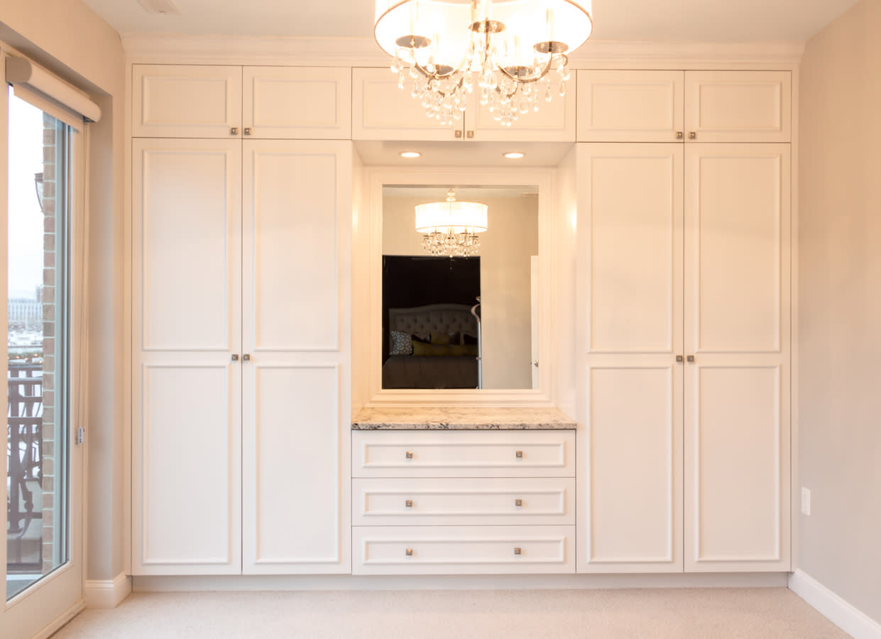 Custom built-in white wardrobe with integrated vanity, mirror, featuring shaker-style doors