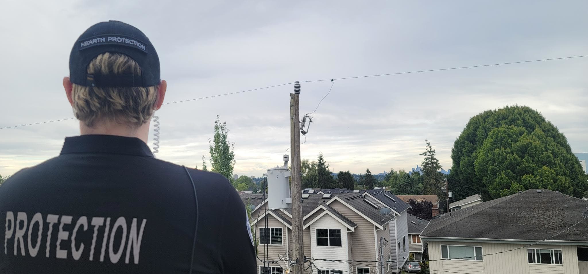 A HEARTH Protective Services Agent wearing an earpiece surveys the street from an elevated position.