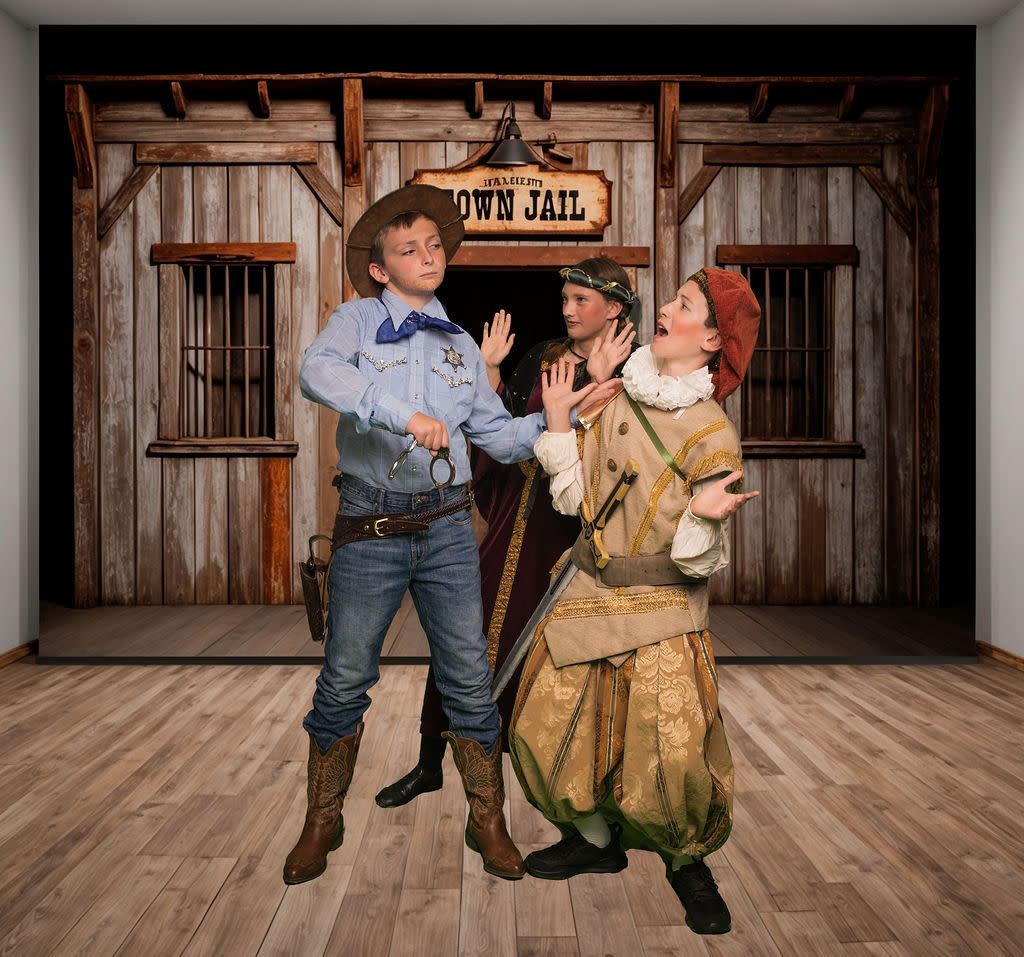three young actors in various costumes outside an old west style town jail