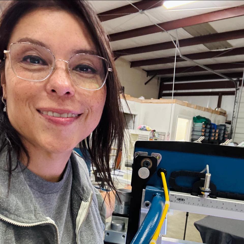 Lucy Espindola operating screen-printing equipment at It’s So Cute, LLC.