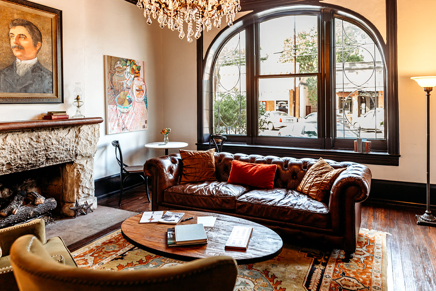 parlor with large, curved antique window, fireplace, sofa and table