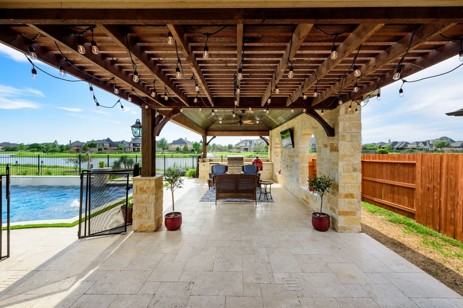 Custom outdoor living space with pergola, travertine pavers and pool by Sunset Pools in Katy, Texas