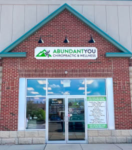 Front entrance of Abundant You Chiropractic & Wellness with clinic signage, contact info, and a list of conditions we help