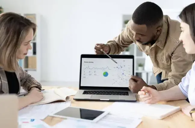 photo of colleagues reviewing data on a laptop screen