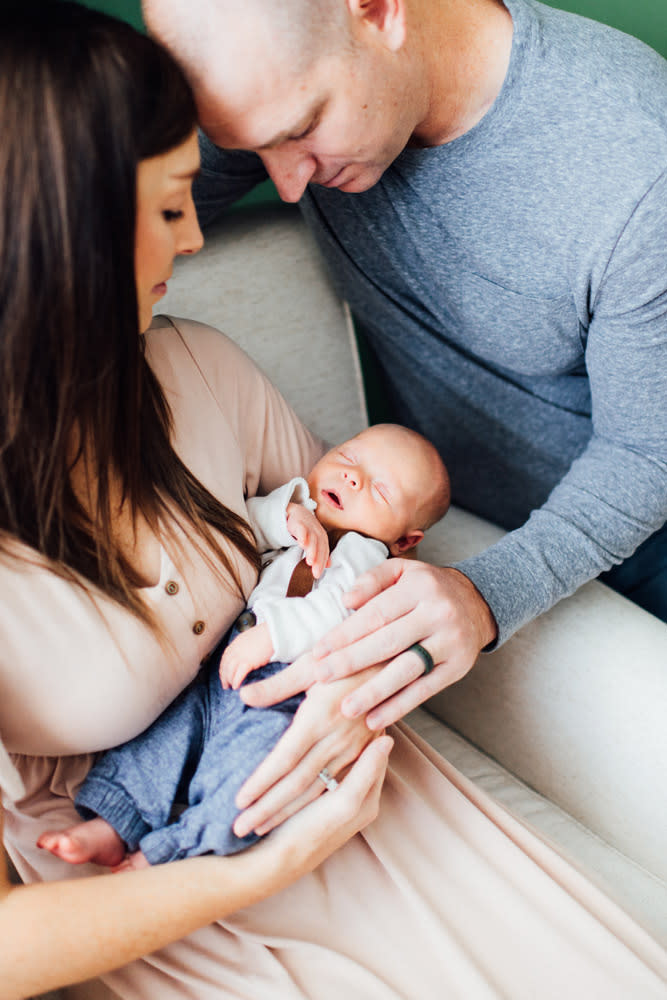Parents gently cradle their newborn baby during an intimate in-home lifestyle newborn session.