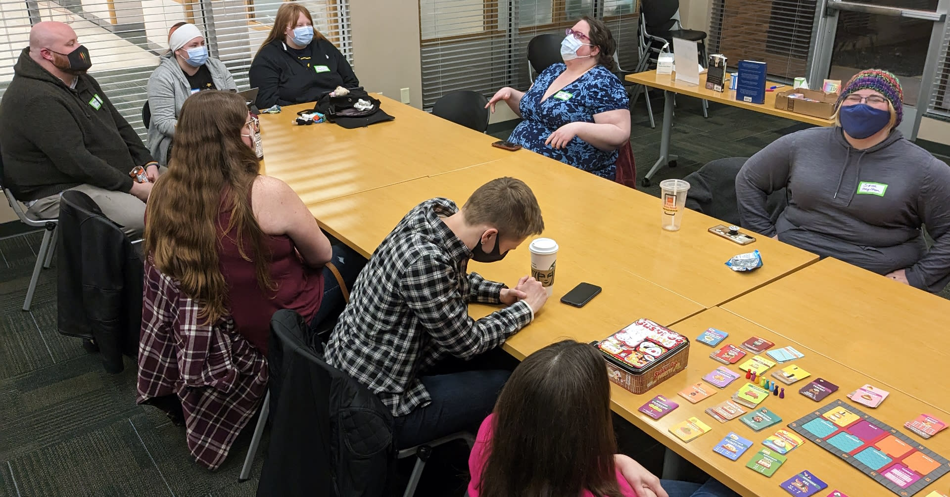A group of people wearing masks and enjoying conversation and board games.