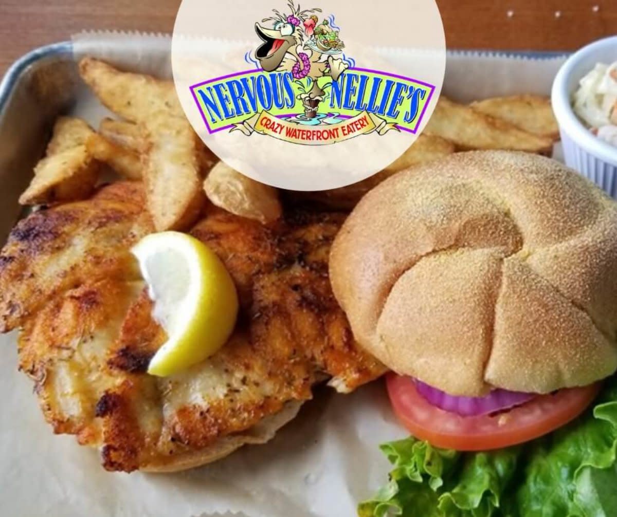 Fried fish sandwich with lemon wedge and potato wedges served at Nervous Nellie's waterfront eatery.