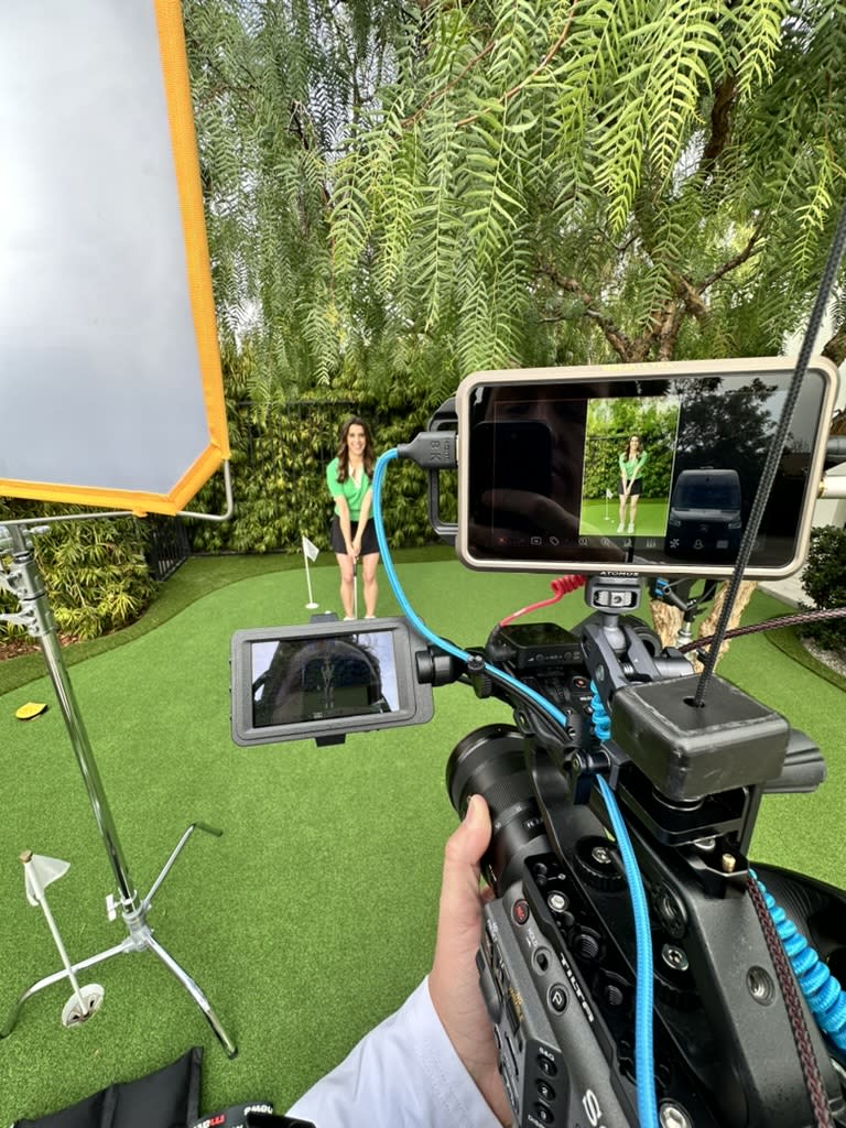 Camera operator filming a woman for a podcast trailer on an outdoor set.