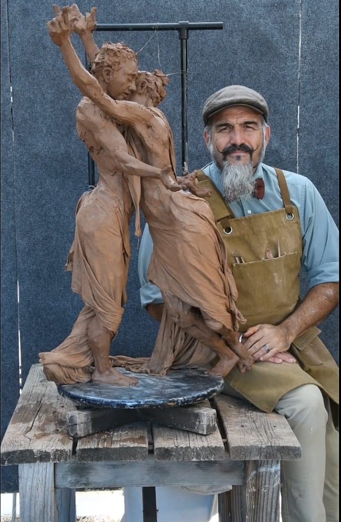 Artist with clay sculpture of two lovers dancing