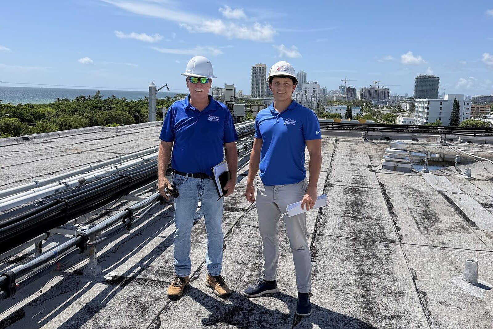 Merrick Molsbee and Dell Powell of Molsbee Roofing in hard hats on a commercial flat roof