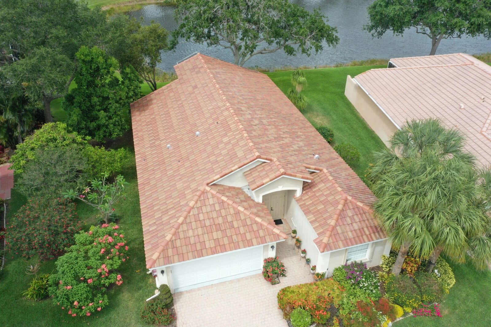 Red tile roof on a one-story lakeside home with a flowering front garden in Via Verona, Delray Beach