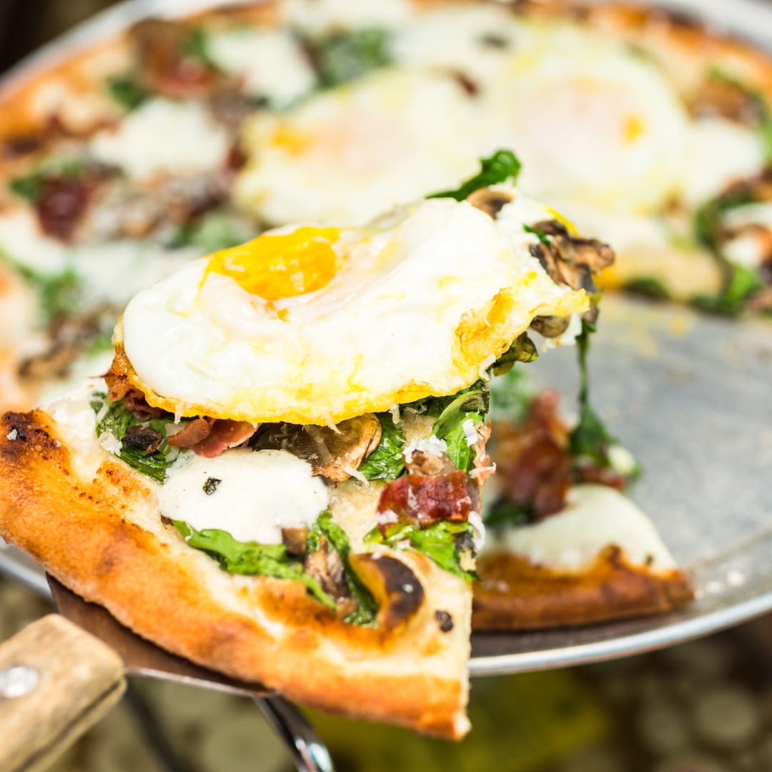 Breakfast pizza served at a bed and breakfast, featuring eggs, cheese, and savory toppings