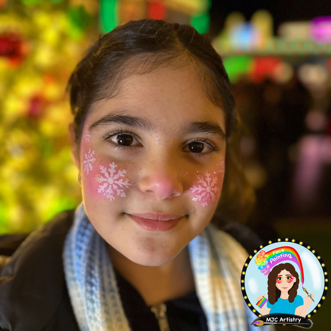 Girl with pink cheek face paint decorated with white snowflakes at an event in Vancouver
