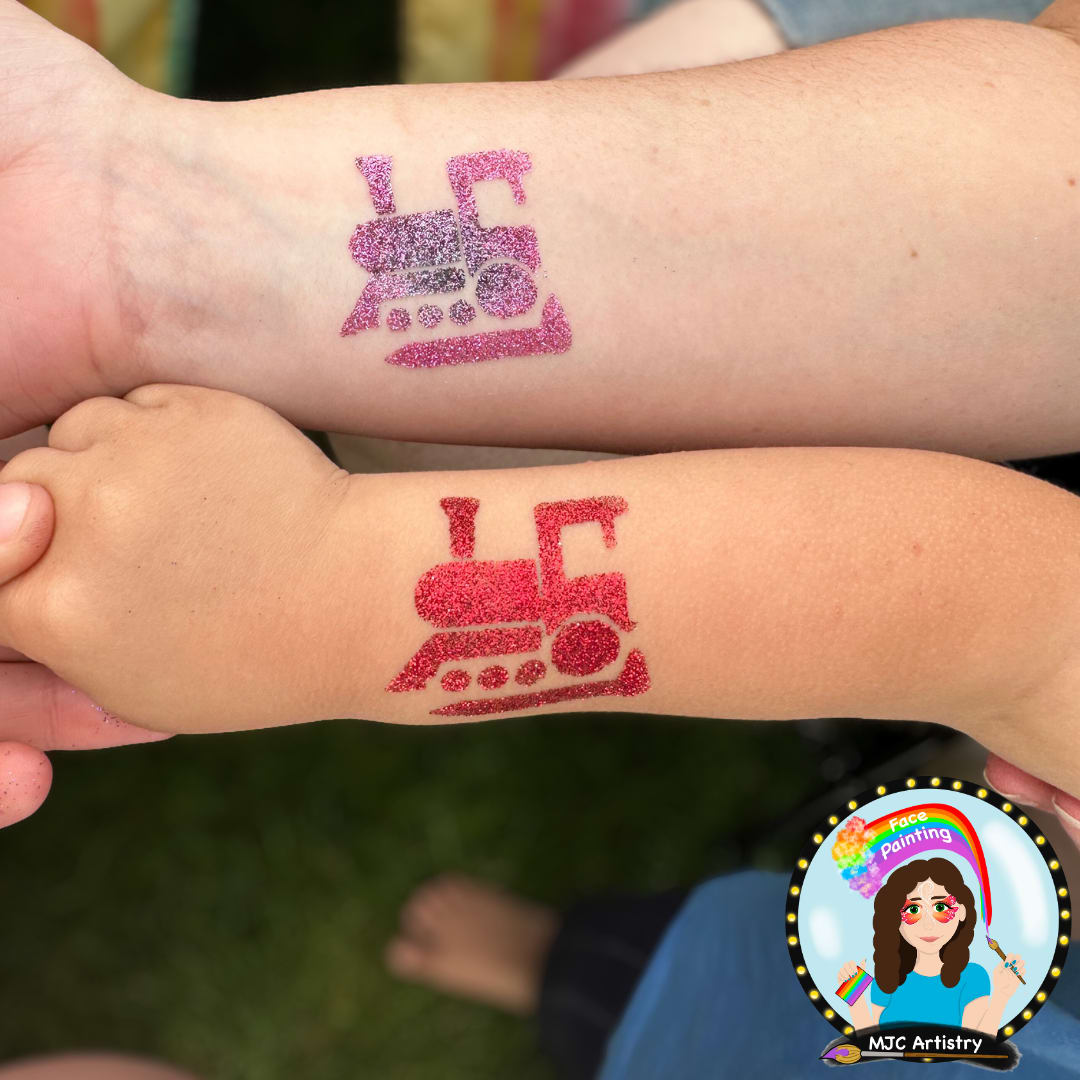 pink and black sparkly train tattoo on adult art and red sparkly train tattoo on kids are at community event in Port Moody