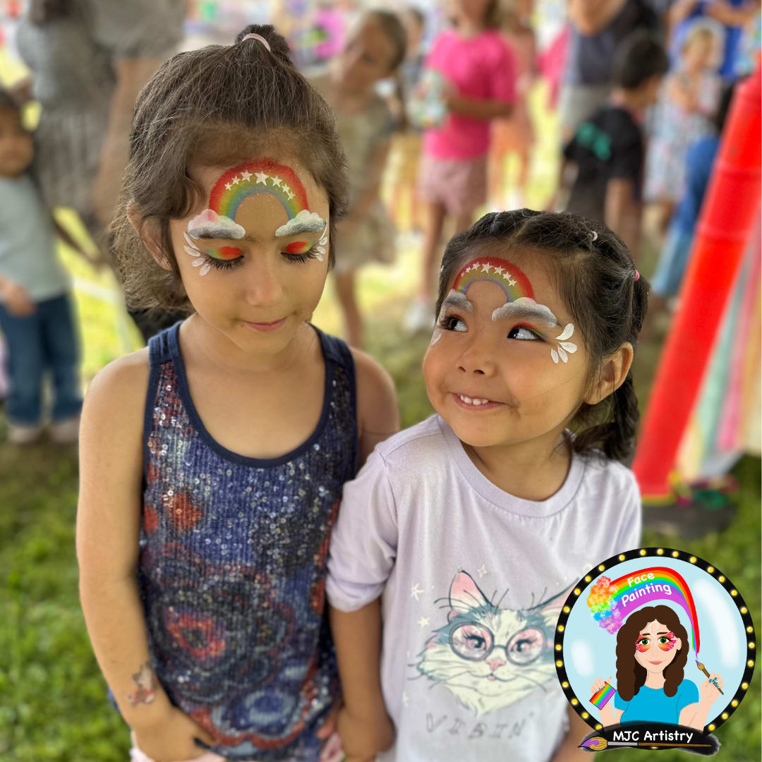 two girls with brown hair wearing a rainbow face paint with cloud eyebrows at a community event in maple ridge