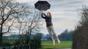 In this image, Carole is flying and holding an umbrella.