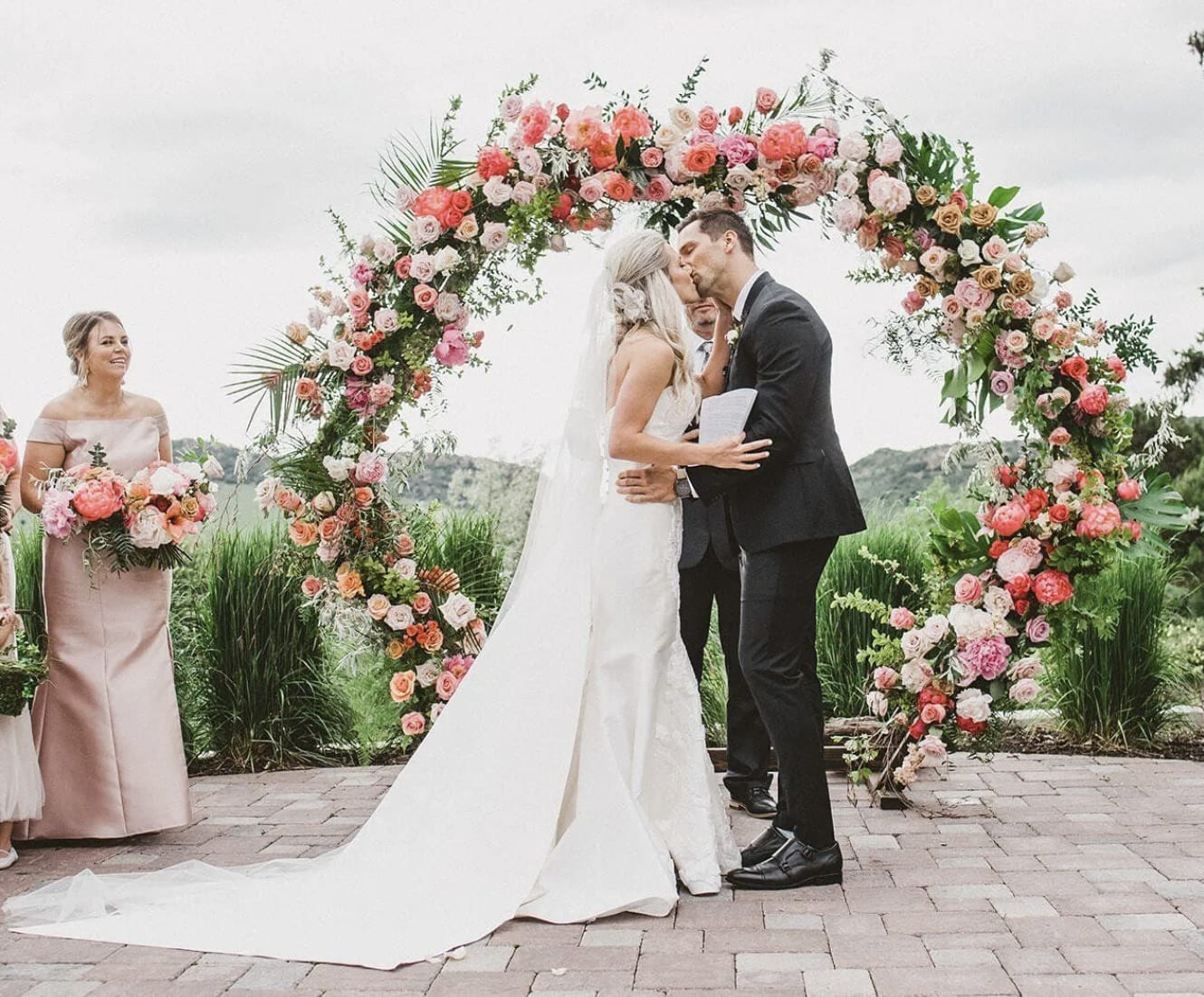 Bride and groom kissing in front of their floral arch at their wedding ceremony.