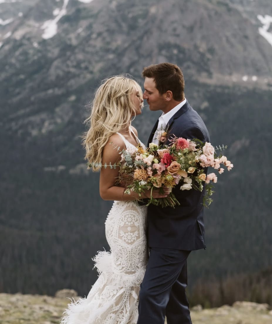 Bride and groom with bouquet in front of the mountains.