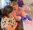 Two women looking at a model of human teeth for a dental demonstration.