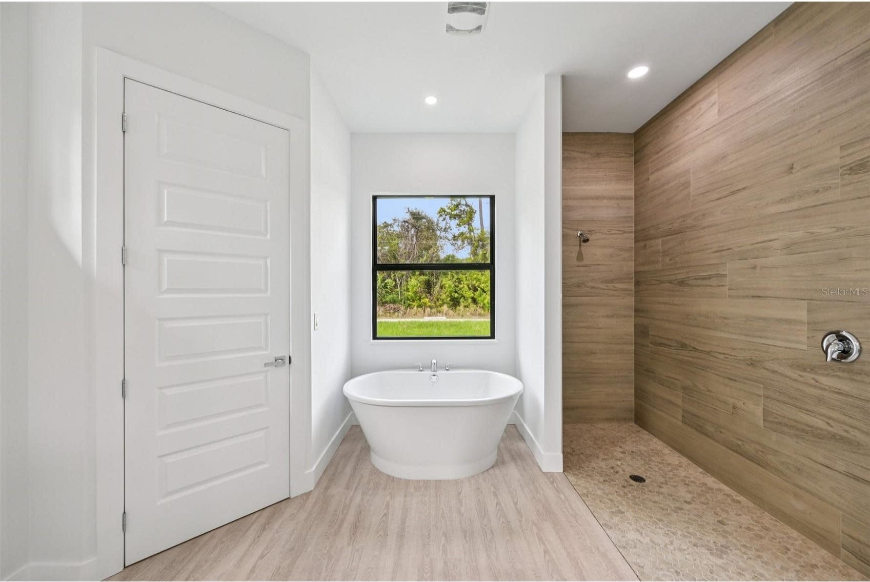 Modern bathroom with freestanding tub and wood-look tile shower by Sosnin Builders