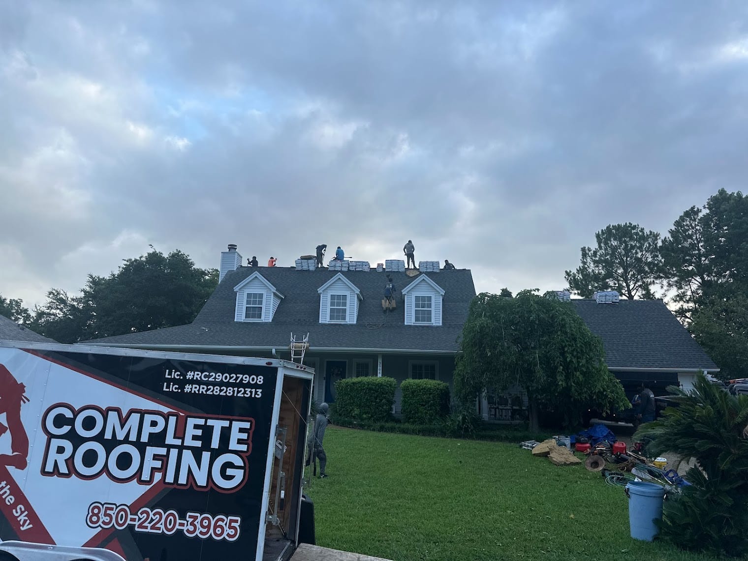 Complete Roofing LLC branded trailer and yard sign at a finished residential shingle roof replacement in Gulf Breeze, Santa R