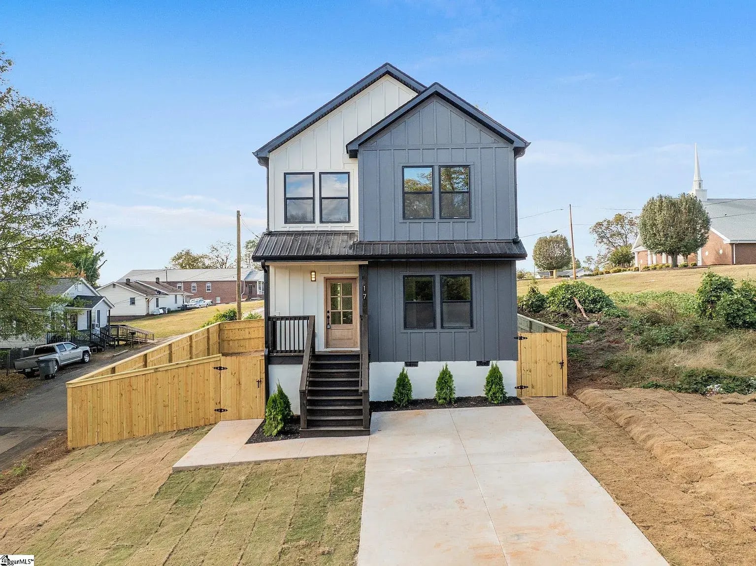 Modern two story home by Heroic Builders featuring gray and white board and batten siding, black windows, and a covered entry