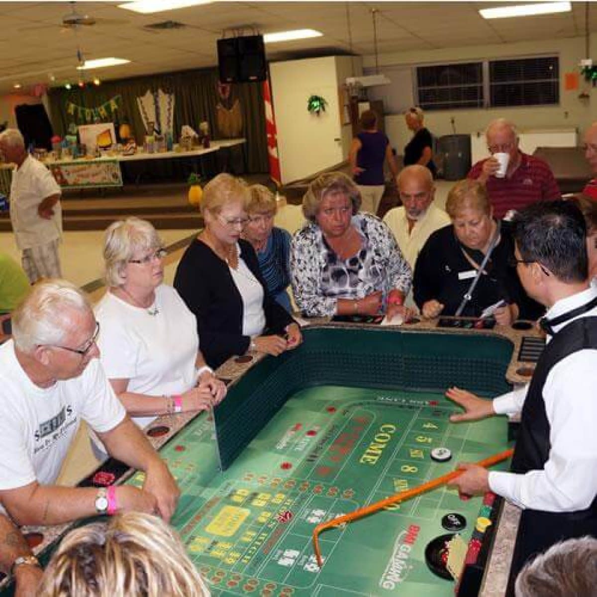 Seniors enjoying casino night with craps table at indoor social event