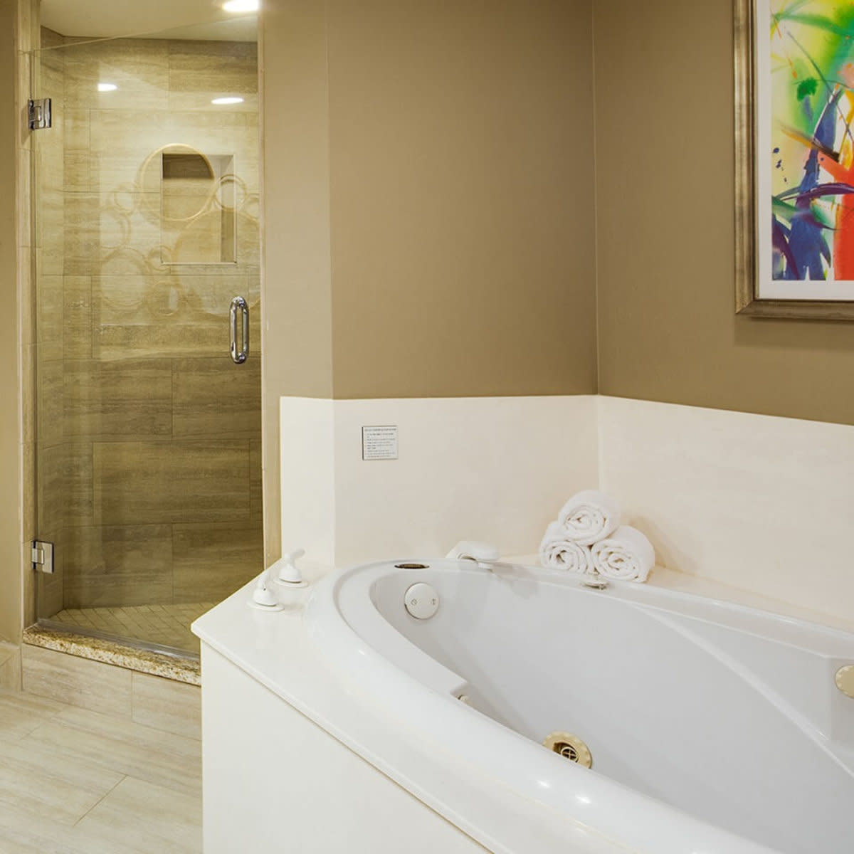 Bathroom with whirlpool tub, rolled towels and walk-in glass shower